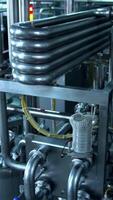 Milk and water pipelines at a modern dairy factory. Tanks, pipes and faucets close up. Gradual lifting above the factory equipment. Vertical video