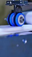 Little blue rollers spin to make recesses on the diaper surface. Quickly rotating shafts of the conveyor line at the diaper manufacturing close up. Vertical video