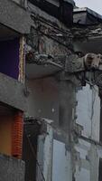Hydraulic claw of excavator breaks easily the floors of an old building. Falling debris create thick dust cloud at the deconstruction site. Vertical video
