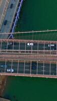 Multiple cars moving quickly over the huge bridge and roads under it. Heavy traffic and car parking lots in a big city. Top view. Vertical video