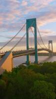 Quickly moving cars along the huge beautiful Bridge. Bronx-Whitestone Bridge crossing East River at the backdrop of amazing sky. Vertical video
