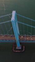 Rising high above the Whitestone Bridge. Numerous cars and lorries riding along the bridge and motorways of the island. Vertical video
