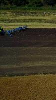 Plow Attached To A Tractor On A Field. Modern farming tractor which plowing agriculturafield Vertical video