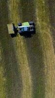 Agricultural Machines Working In The Field. Cube baler tractor discharges a fresh wheat bale during harvesting Vertical video