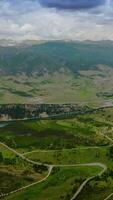 Amazingly beautiful green valleys near the rivers in mountainous region. Little town at the foot of mountain in Colorado. Dramatic sky over the mountain range at backdrop. Vertical video