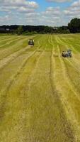 Agricultural Machines Working In The Field. Cube baler tractor discharges a fresh wheat bale during harvesting Vertical video