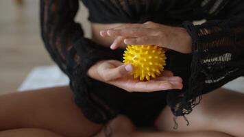 A Yellow Spiky Massage Ball Being Held Firmly in Hands for Enhanced Wellbeing and Comfort video