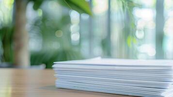 A stack of papers on a table in front of a window photo