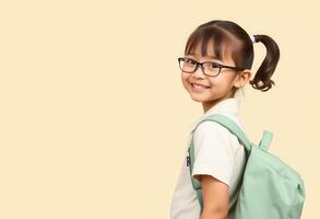 A young girl wearing glasses and a backpack, smiling at the camera photo