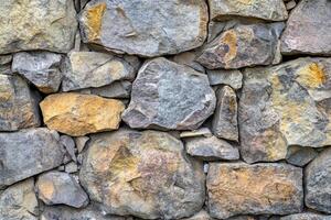 Close-up of a Rough Stone Wall with Irregular Shapes and Colors photo