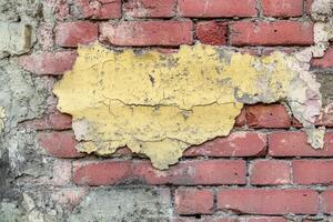 Weathered Brick Wall with Peeling Yellow Paint photo