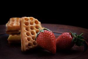Viennese waffles in the shape of a heart lie on a clay plate. Viennese waffles with strawberries. photo