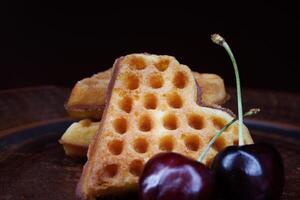Viennese waffles in the shape of a heart lie on a clay plate. Viennese waffles with cherries. photo