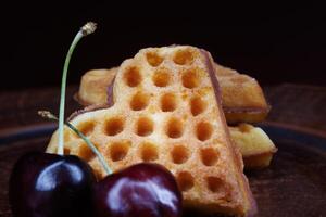 Viennese waffles in the shape of a heart lie on a clay plate. Viennese waffles with cherries. photo
