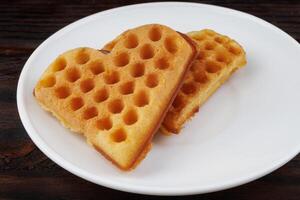 Two Viennese waffles lie on a white plate. Viennese waffles in the shape of a heart. photo