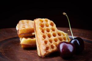 Viennese waffles in the shape of a heart lie on a clay plate. Viennese waffles with cherries. photo