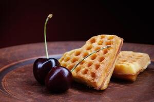 Viennese waffles in the shape of a heart lie on a clay plate. Viennese waffles with cherries. photo