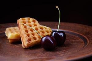 Viennese waffles in the shape of a heart lie on a clay plate. Viennese waffles with cherries. photo