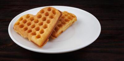 Two Viennese waffles lie on a white plate. Viennese waffles in the shape of a heart. photo