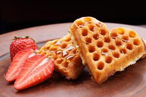 Viennese waffles drizzled with honey in the shape of a heart lie on a clay plate. Viennese waffles with cut strawberries. photo