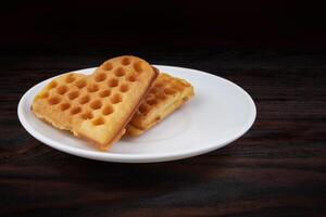 Two Viennese waffles lie on a white plate. Viennese waffles in the shape of a heart. photo