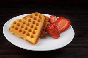 Viennese waffles with strawberries lie on a white plate. Viennese waffles in the shape of a heart. photo