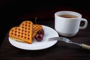 Viennese waffles with cherries lie on a white plate. Viennese waffles in the shape of a heart. photo