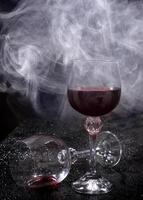 Smoke around a glass of wine. A glass of red wine stands on the surface, an empty glass lies next to it. photo