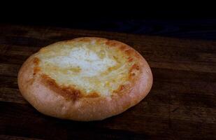 Khachapuri. Pie with cheese on a wooden background. Cheese bun. photo