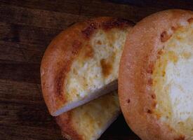 Khachapuri. Bun with cheese on a wooden background. Cheese pie. photo