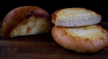 Khachapuri. Bun with cheese on a wooden background. Cheese pie. photo