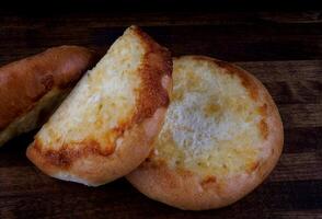 Khachapuri. Bun with cheese on a wooden background. Cheese pie. photo