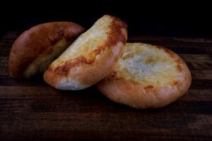 Khachapuri. Bun with cheese on a wooden background. Cheese pie. photo