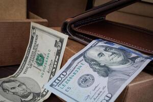 A leather wallet with dollar bills lies on paper boxes. photo