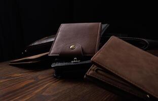 Many beautiful leather wallets lie on a wooden surface. photo