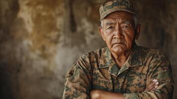 Elderly Pacific Islander Veteran Posed in Military Uniform with Folded Arms Against Rustic Background photo