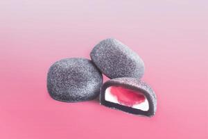 Mochi dessert. A few black Mochi with red berry filling Isolated on a gradient pink Background. photo