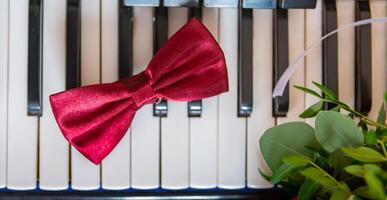 Red Satin Bow Tie Resting on Black and White Piano Keys in a Stylish Setting. photo