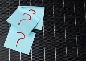 Drawn question marks on stickers, black background. Searching for truth and answering questions photo