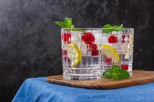 Raspberry cocktail with ice in a glass on a wooden tray photo