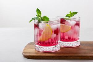 Raspberry cocktail with ice in a glass on a light background photo