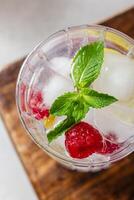 Raspberry cocktail with ice in a glass on a light background photo