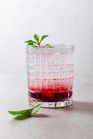 Cocktail with ice in a glass on a light background photo