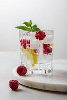 Raspberry cocktail with ice in a glass on a light background photo