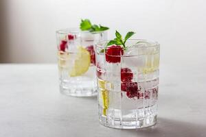 Raspberry cocktail with ice in a glass on a light background photo