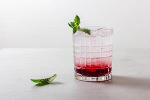 Cocktail with ice in a glass on a light background photo