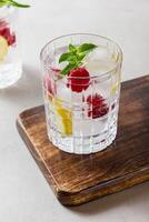 Raspberry cocktail with ice in a glass on a light background photo