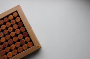 Cardboard box with rows of wine corks on white surface turned on a side of image with copy space photo