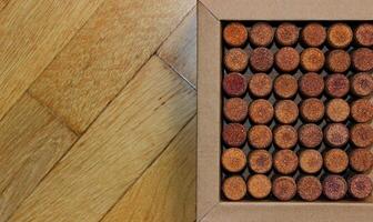 Cardboard box with lined out wine corks on wooden surface on a side of image concept for postcard or wallpaper photo