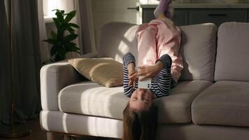 Little girl child lying on sofa using mobile phone smartphone gadget technology online meeting communication gesticulating conversation talk call chat daughter kid home internet network virtual video